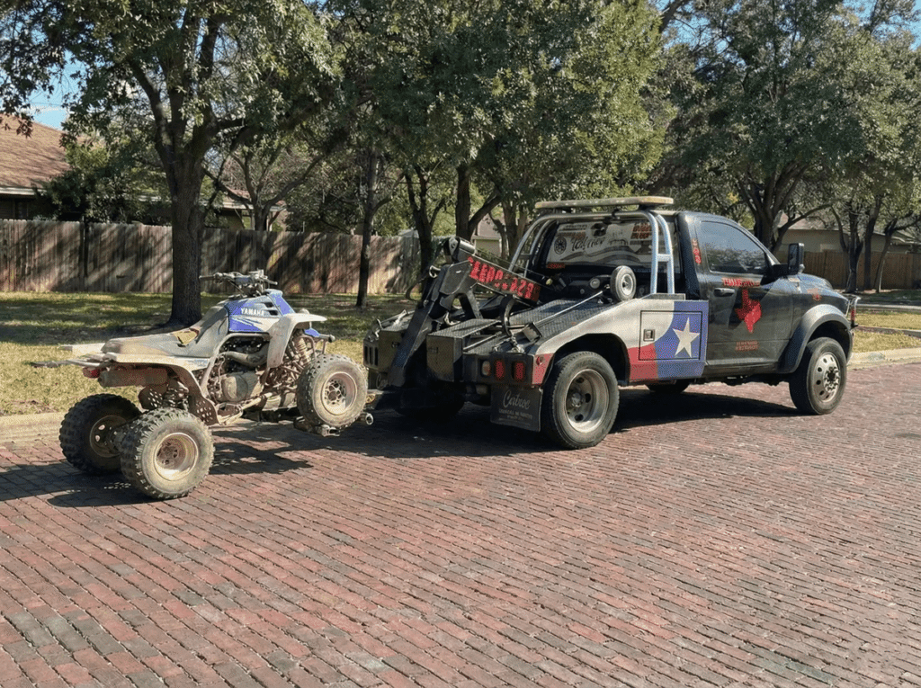 image of a dusty old atv being towed by a tow truck