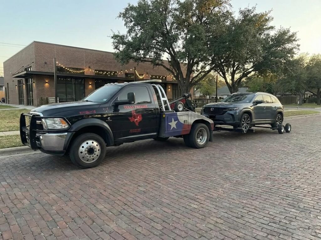 Black tow truck towing an AWD SUV Honda